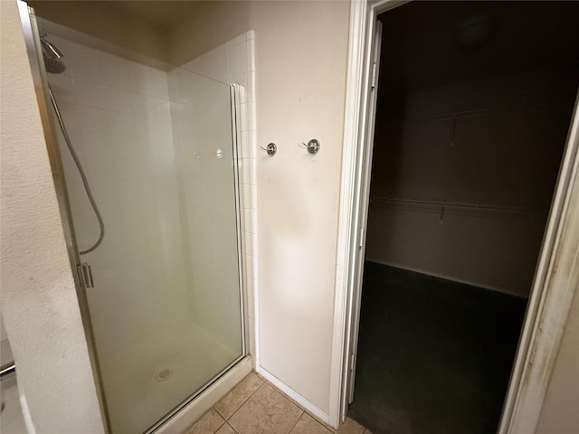 full bath featuring tile patterned floors, a walk in closet, and a stall shower