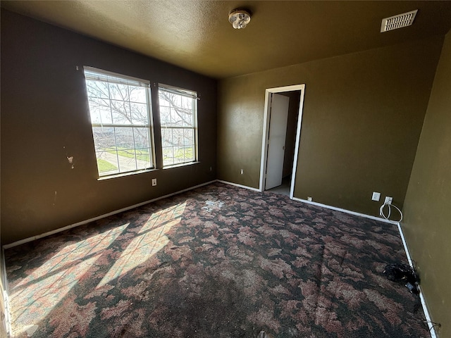 empty room featuring visible vents, baseboards, a textured ceiling, and carpet flooring