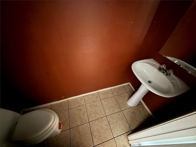 bathroom featuring a sink, baseboards, toilet, and tile patterned flooring