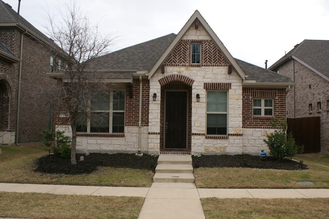 view of front facade with brick siding, stone siding, and a shingled roof