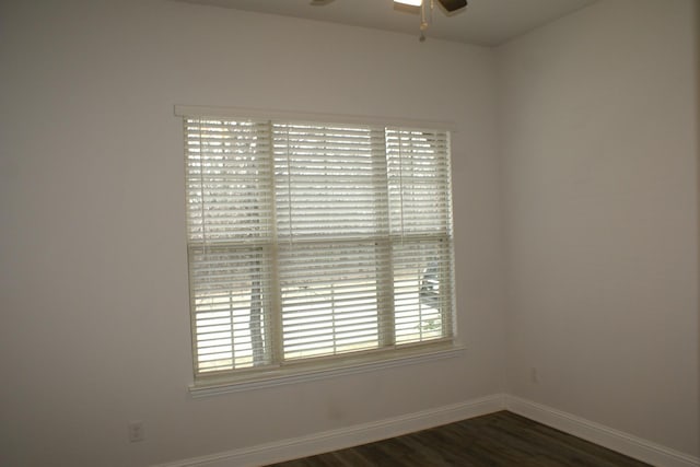 unfurnished room with ceiling fan, baseboards, and dark wood-style flooring