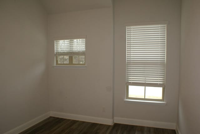 spare room featuring baseboards and dark wood-type flooring