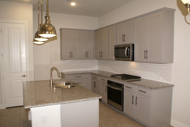 kitchen with backsplash, light stone countertops, pendant lighting, stainless steel appliances, and a sink