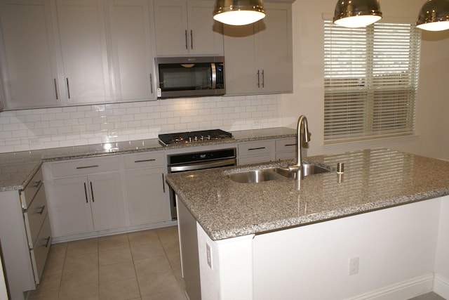 kitchen featuring light tile patterned floors, decorative backsplash, light stone counters, stainless steel appliances, and a sink