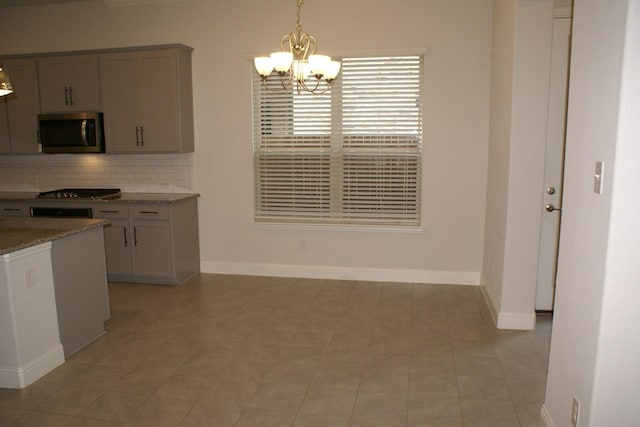 kitchen with tasteful backsplash, decorative light fixtures, stone counters, appliances with stainless steel finishes, and a notable chandelier