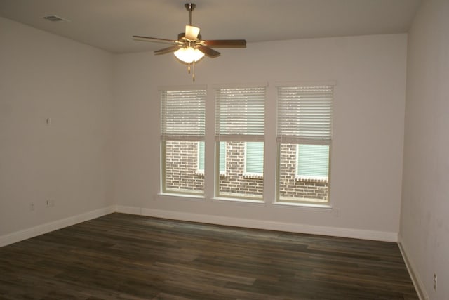 empty room featuring visible vents, baseboards, a ceiling fan, and dark wood-style flooring