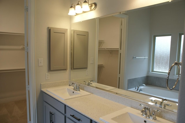 bathroom with double vanity, a walk in closet, and a sink