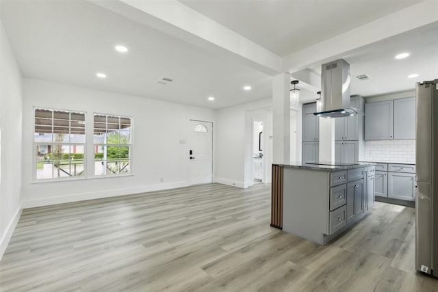 kitchen with visible vents, light wood-type flooring, gray cabinetry, island exhaust hood, and tasteful backsplash