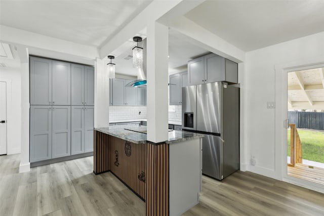 kitchen featuring light wood-style flooring, stainless steel fridge with ice dispenser, stone countertops, gray cabinets, and backsplash