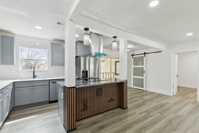 kitchen featuring visible vents, a barn door, gray cabinets, appliances with stainless steel finishes, and a sink