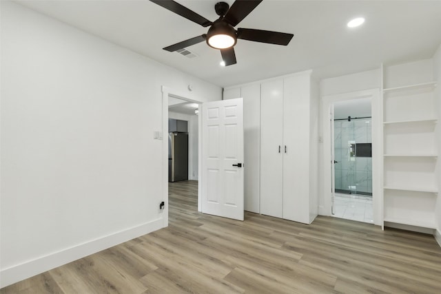 unfurnished bedroom with visible vents, baseboards, ensuite bath, light wood-style flooring, and freestanding refrigerator