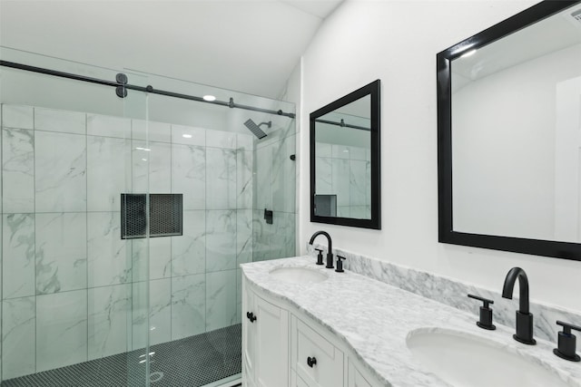 full bathroom with double vanity, a marble finish shower, and a sink