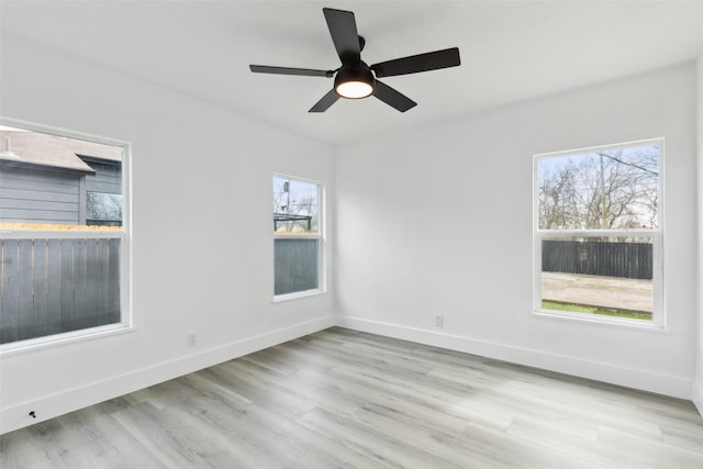 unfurnished room with wood finished floors, a healthy amount of sunlight, baseboards, and ceiling fan