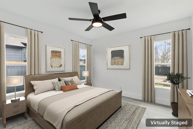 bedroom featuring baseboards, light wood-style floors, and ceiling fan