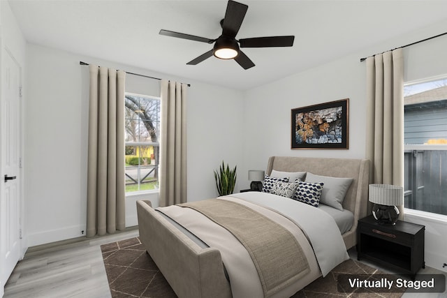 bedroom with baseboards, multiple windows, wood finished floors, and a ceiling fan