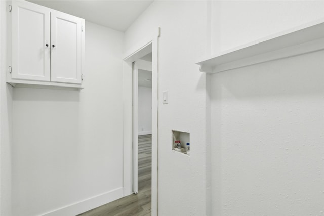 laundry room with cabinet space, wood finished floors, baseboards, and washer hookup