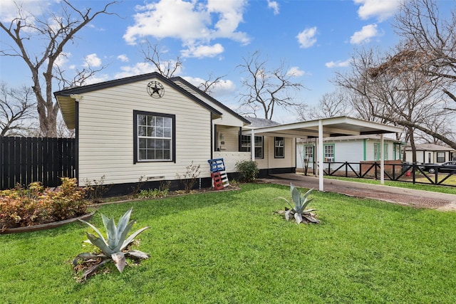 view of front of property featuring an attached carport, fence, and a front yard