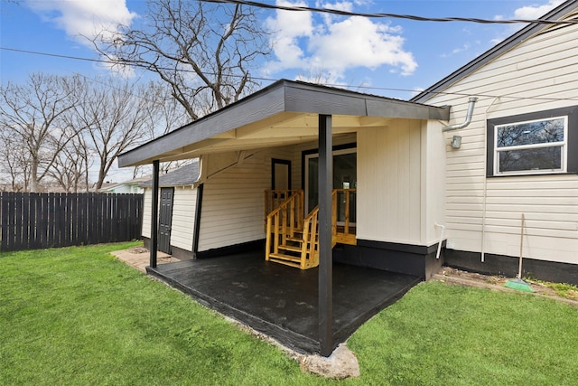 entrance to property featuring a lawn and fence