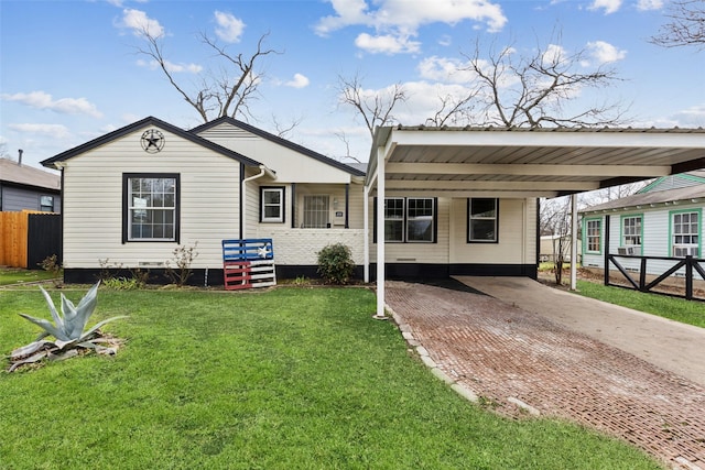 view of front of house with decorative driveway, a front lawn, and fence