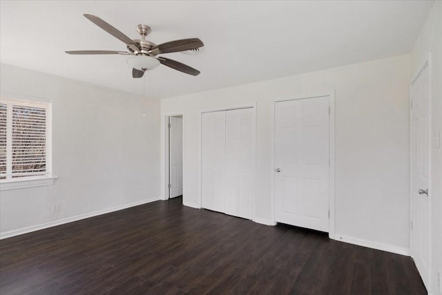 unfurnished bedroom featuring baseboards, a ceiling fan, wood finished floors, and multiple closets