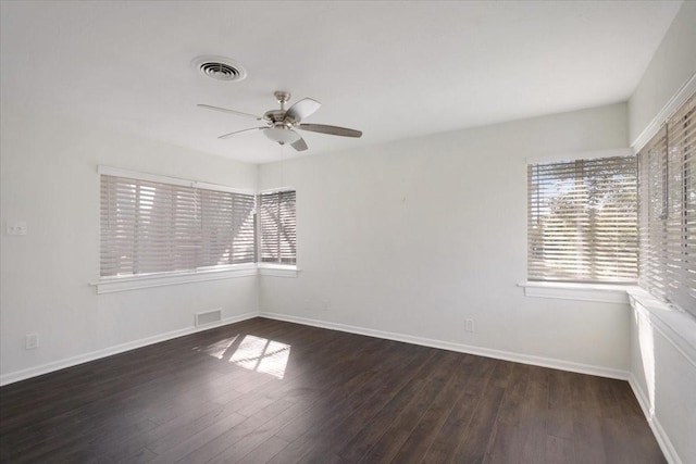 spare room with plenty of natural light, baseboards, visible vents, and wood finished floors