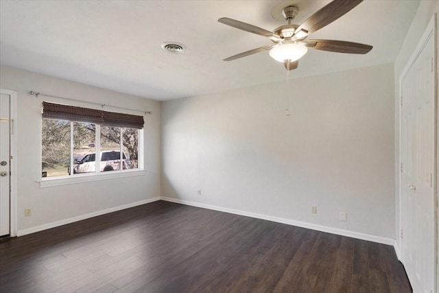 empty room featuring visible vents, baseboards, ceiling fan, and dark wood-style flooring