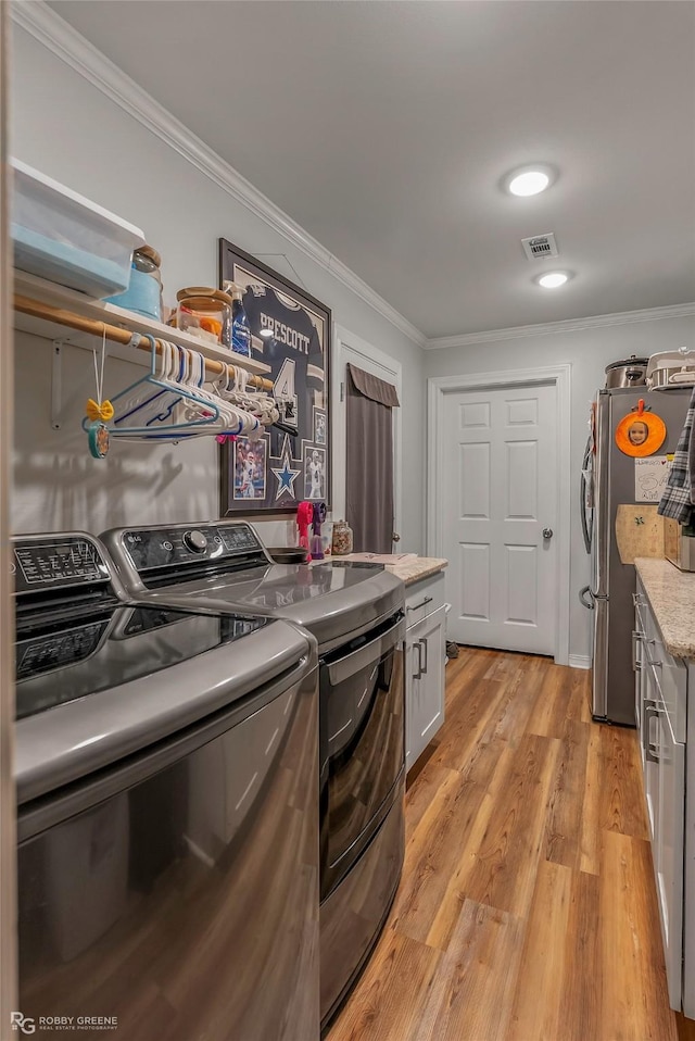 washroom featuring visible vents, independent washer and dryer, light wood finished floors, and ornamental molding