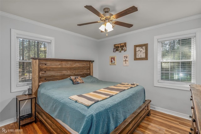 bedroom featuring baseboards, wood finished floors, and crown molding