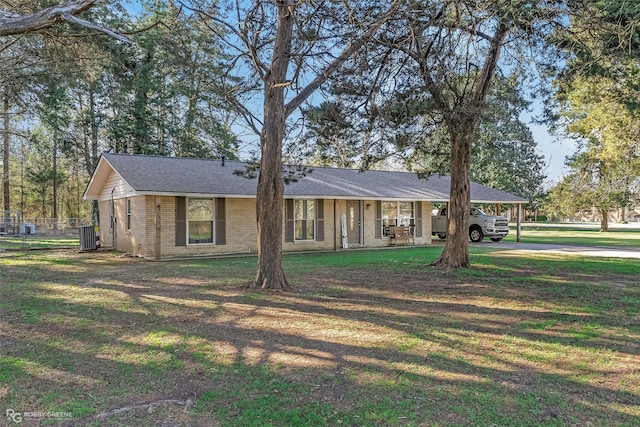 ranch-style home with brick siding, an attached carport, central AC, and a front yard