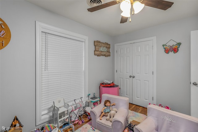 playroom with wood finished floors, a ceiling fan, and visible vents