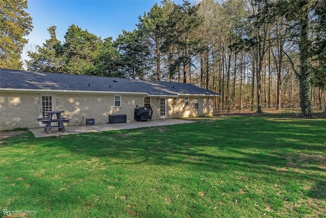 rear view of house with a yard, fence, brick siding, and a patio area