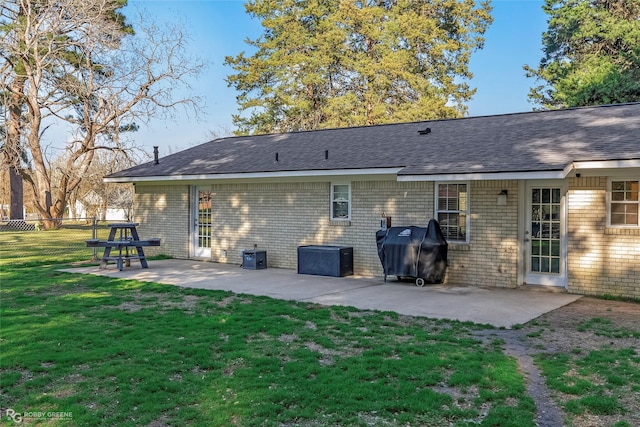 rear view of property featuring a patio, fence, roof with shingles, a lawn, and brick siding