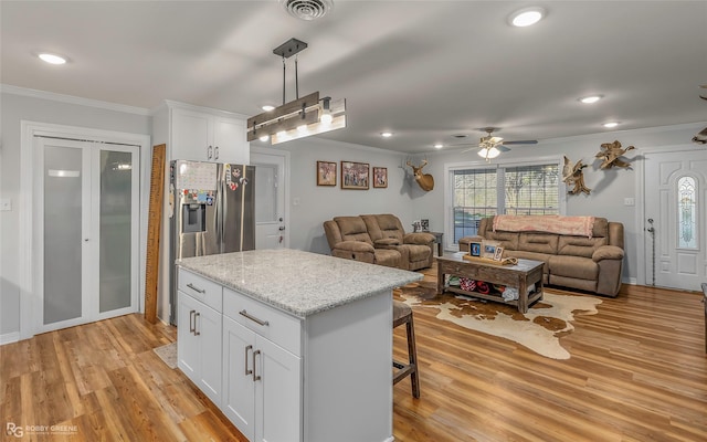 kitchen featuring visible vents, open floor plan, stainless steel refrigerator with ice dispenser, and crown molding