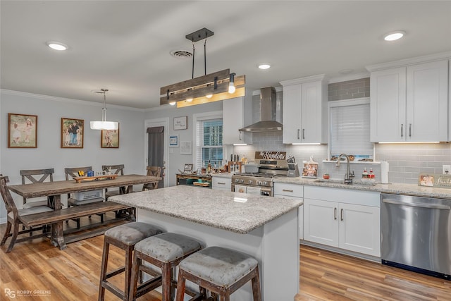 kitchen featuring visible vents, wall chimney range hood, ornamental molding, appliances with stainless steel finishes, and a sink