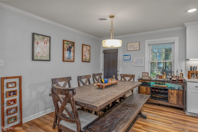 dining space with visible vents, baseboards, light wood-style floors, and crown molding