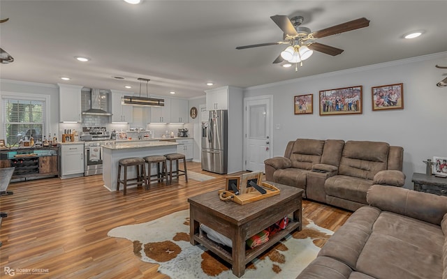 living room with recessed lighting, light wood-type flooring, and crown molding