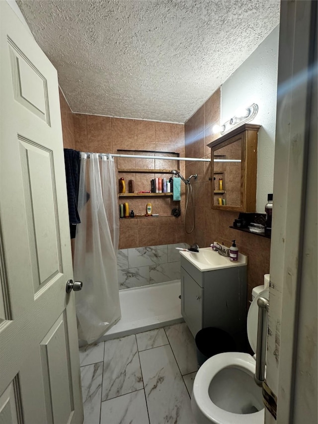 bathroom with vanity, a shower stall, a textured ceiling, toilet, and marble finish floor