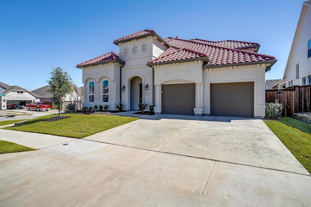 mediterranean / spanish house with a front lawn, a tiled roof, concrete driveway, stucco siding, and an attached garage