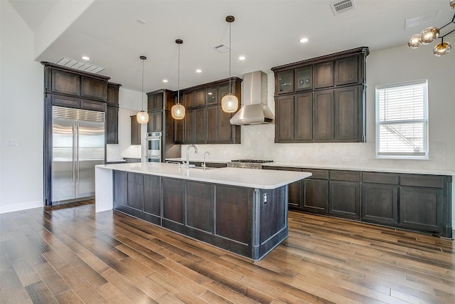 kitchen featuring visible vents, dark wood finished floors, stainless steel appliances, light countertops, and wall chimney exhaust hood