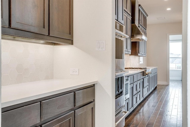 kitchen featuring tasteful backsplash, dark wood finished floors, light countertops, stainless steel gas stovetop, and a warming drawer