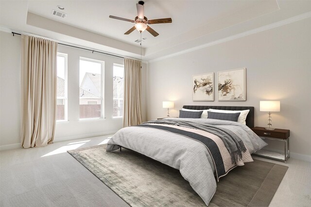 carpeted bedroom featuring visible vents, ornamental molding, baseboards, a raised ceiling, and ceiling fan