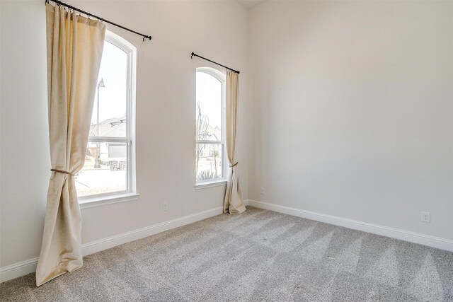 spare room featuring baseboards and light carpet