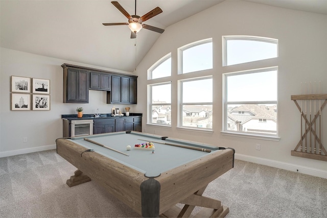 recreation room with high vaulted ceiling, ceiling fan, indoor wet bar, a sink, and light colored carpet