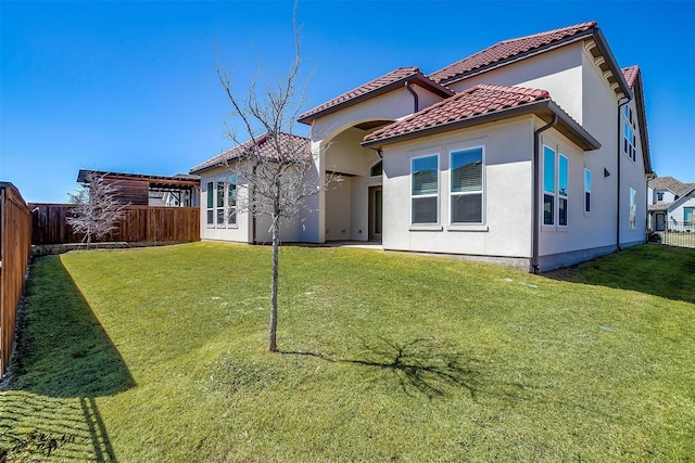 back of property featuring a tile roof, a fenced backyard, a lawn, and stucco siding