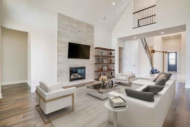 living area featuring visible vents, baseboards, stairs, a fireplace, and wood finished floors