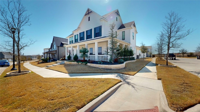 view of front of property with a residential view, covered porch, and a front yard