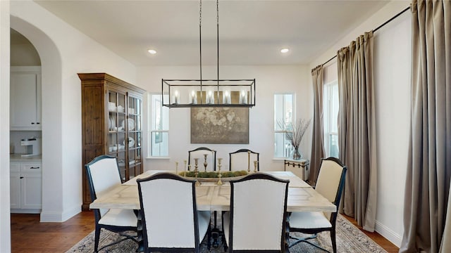 dining space with recessed lighting, baseboards, arched walkways, and dark wood-style floors