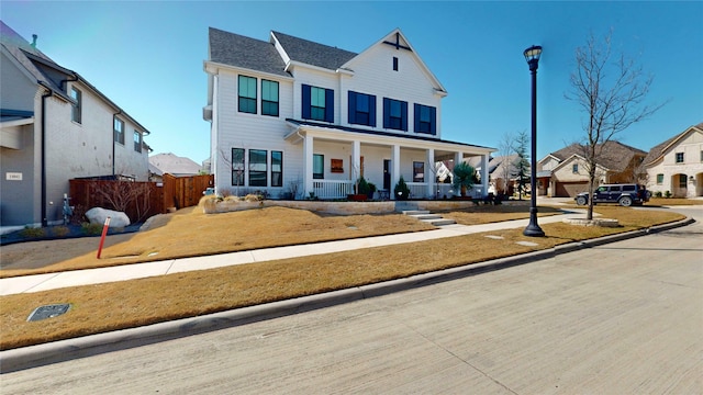 view of front of house with a residential view, covered porch, and fence