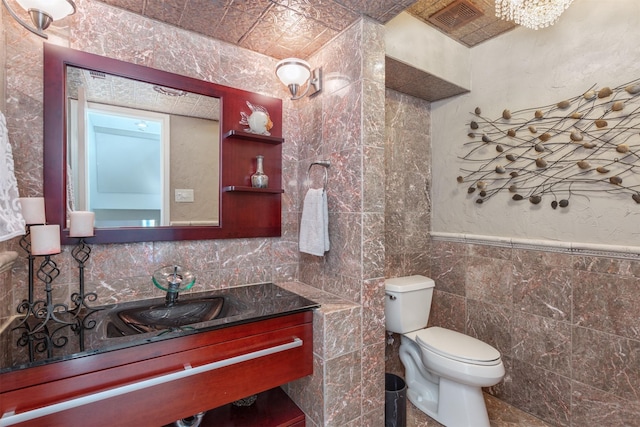 bathroom featuring toilet, tile walls, and vanity