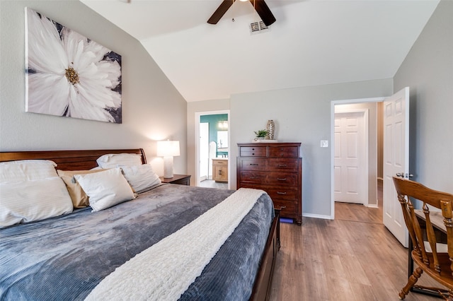 bedroom with visible vents, baseboards, vaulted ceiling, ensuite bathroom, and wood finished floors